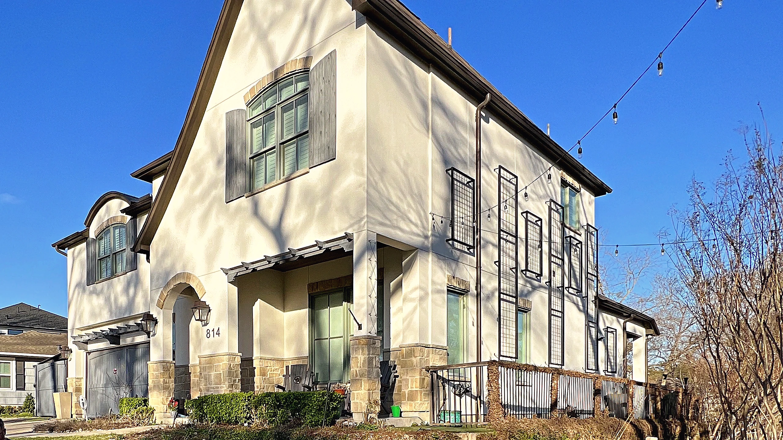 Exterior street view of Houston Heights two-story stucco home with natural stone detail and arched windows