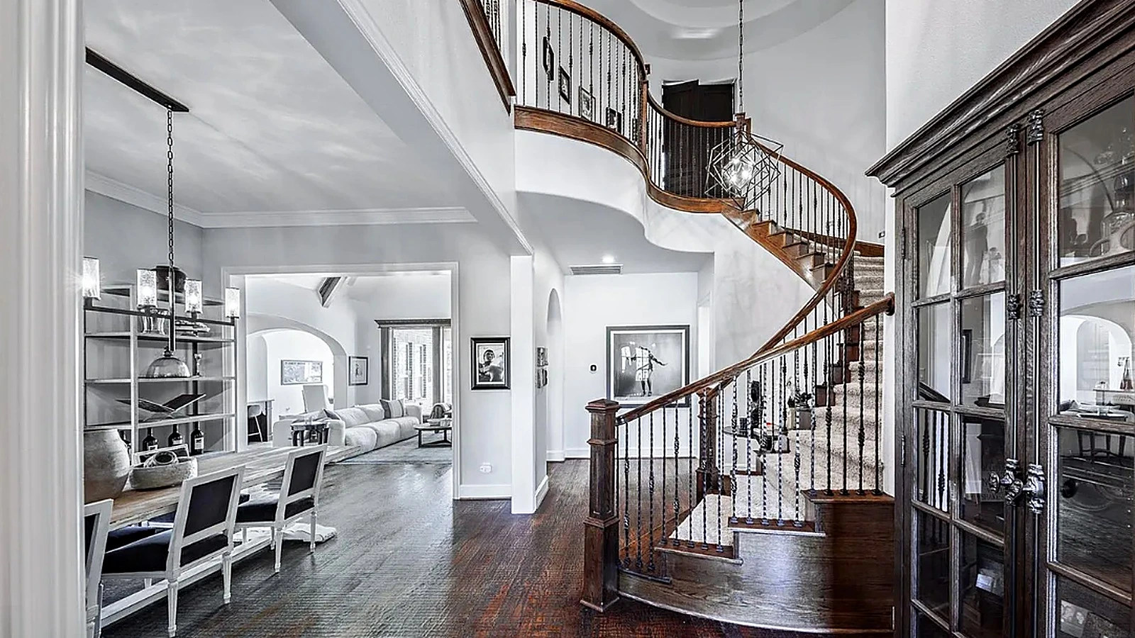 Two-story foyer with curved staircase and wrought-iron balusters in Bellaire home renovation by Bager