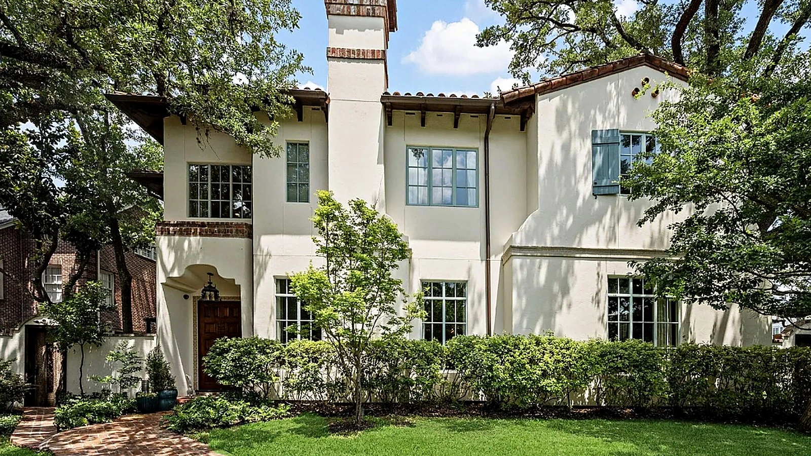 Two-tone cream stucco exterior with clay tile roof, arched entry, and mature oak canopy in Hunters Creek Village