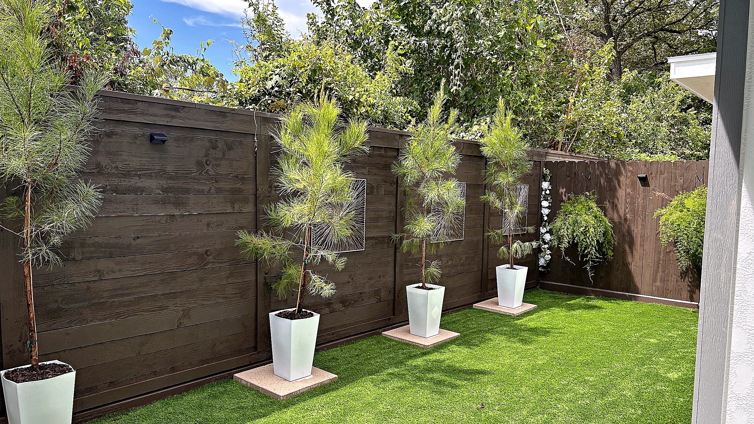 Low-maintenance townhouse courtyard with artificial turf, potted evergreens in white planters, and a wood fence, Spring Valley Village
