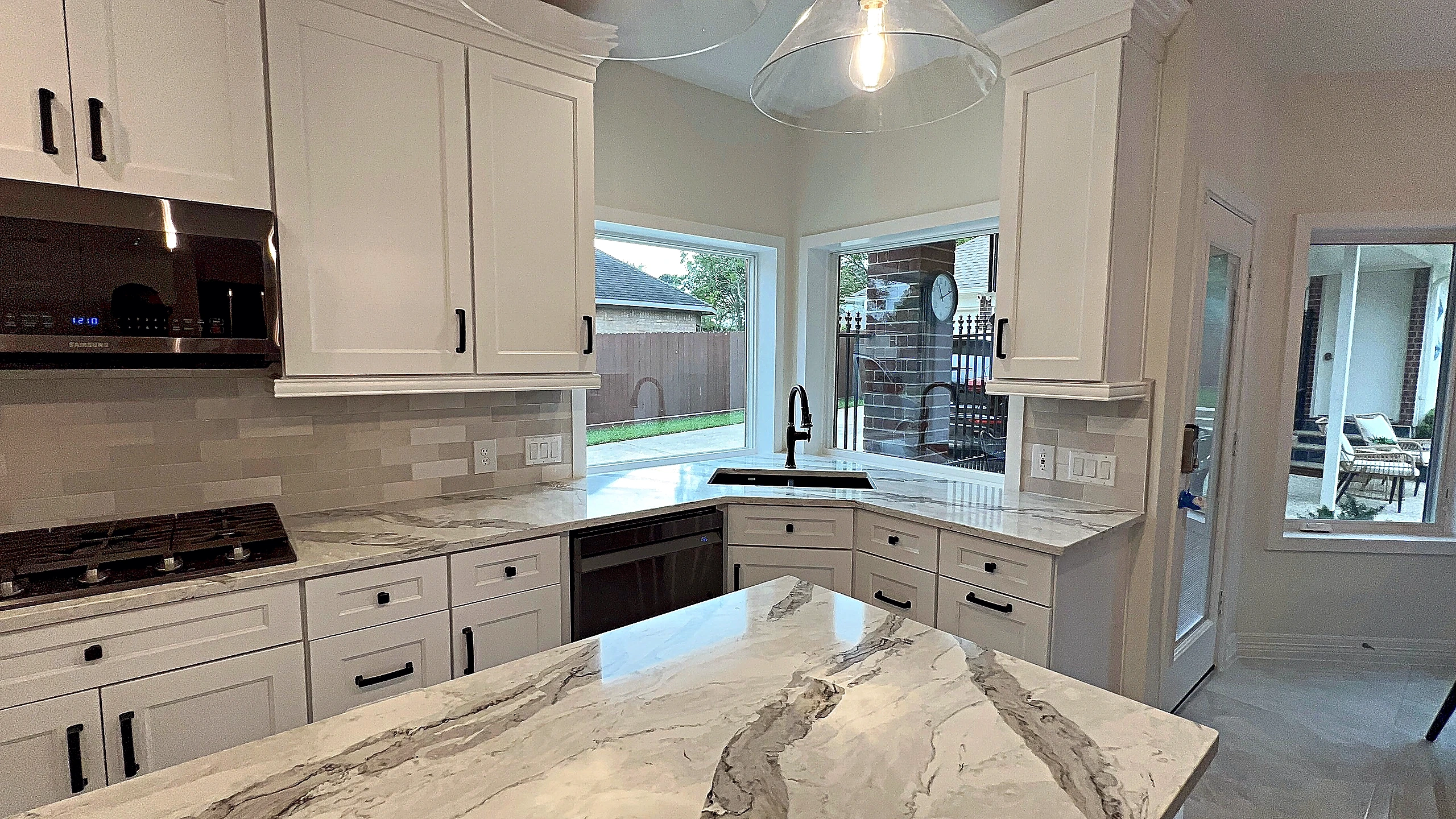 Spring Valley Village kitchen remodel — corner sink wall with natural stone counters and dual windows by Bager
