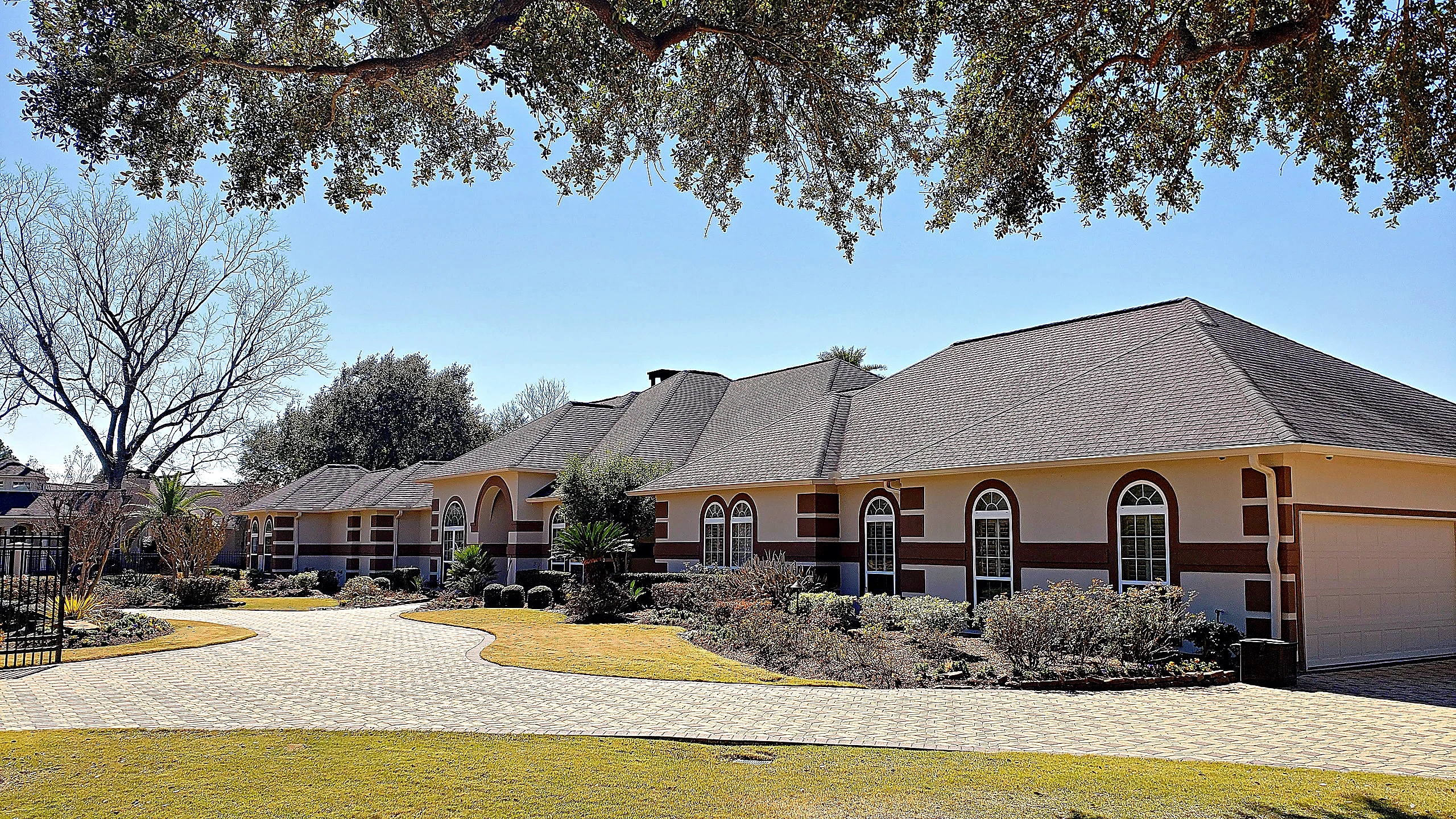 Completed exterior renovation of a classical Tomball estate showing hipped roofline, stucco banding, and arched window series