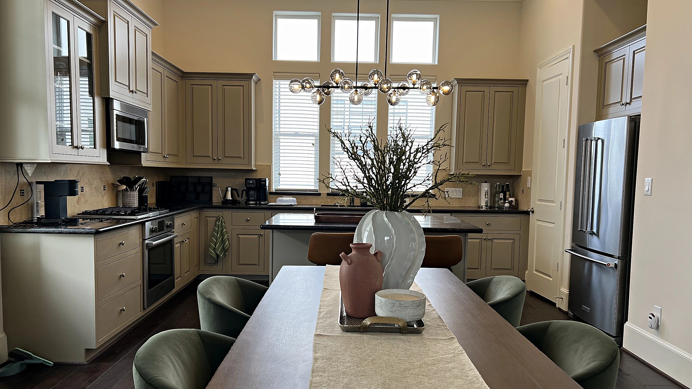 Kitchen and dining space with light cabinetry, dark stone countertops, and a modern chandelier over the table, West University Place