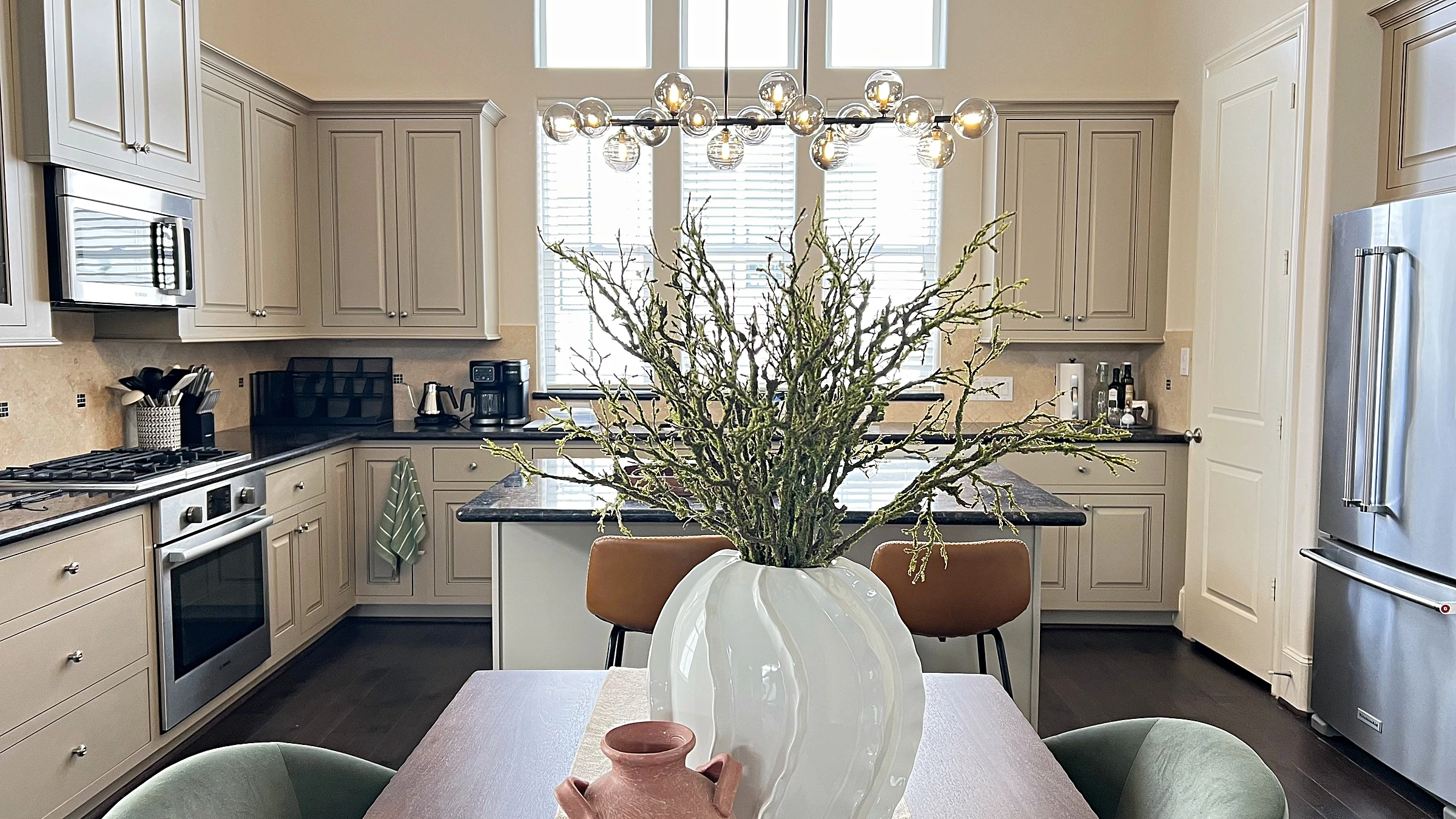 Kitchen with white cabinetry, dark stone countertops, and stainless steel appliances in a West University Place townhome, Houston