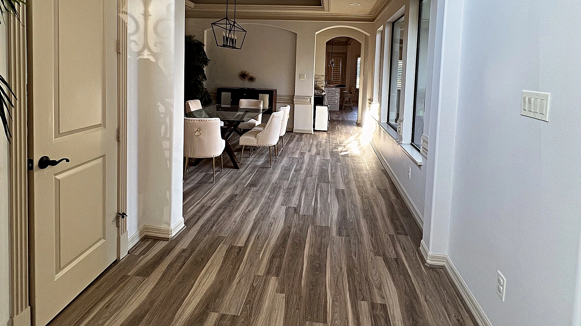 Wood-look plank flooring flowing through an arched hallway into the dining room, flooring by Bager in Houston, TX