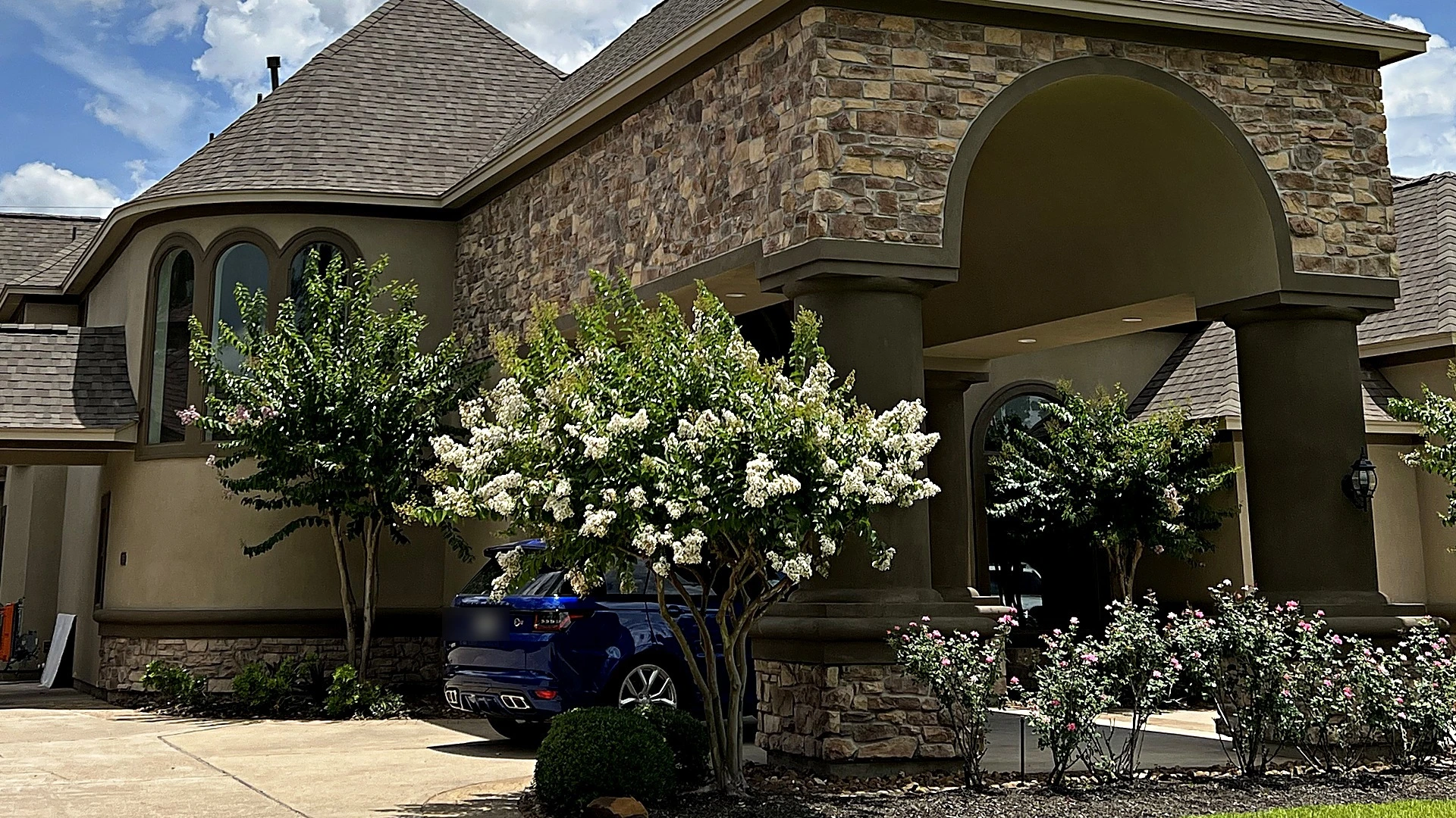 Freshly painted stone and stucco home exterior with an arched entry, house painting by Bager in Houston, TX